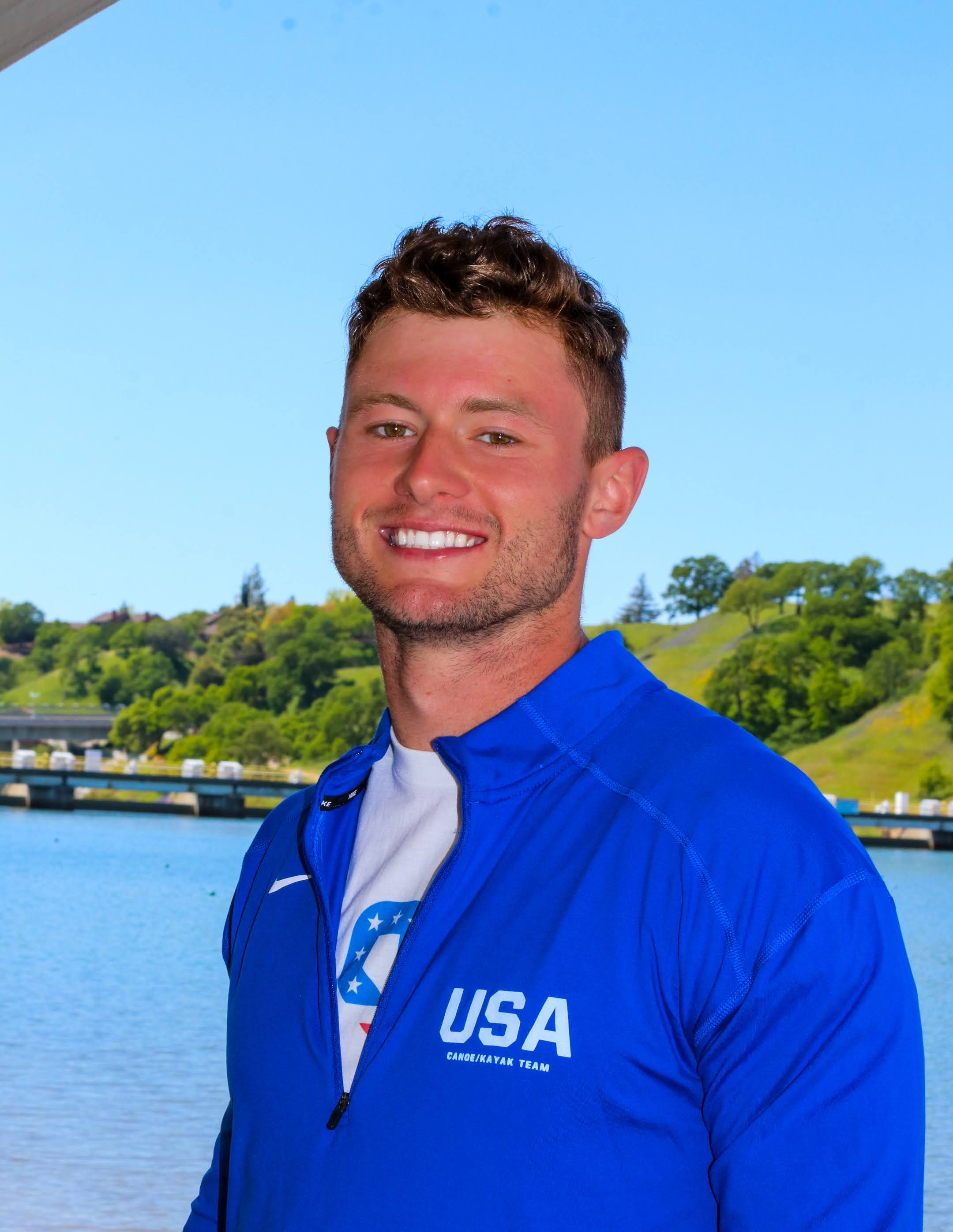 Walker Peck in a USA Canoe/Kayak Team jacket near the water.